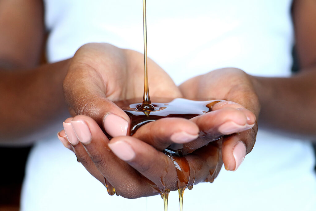 Black African hands cupped catching and holding pouring honey shot for beauty industry, for Phibel Naturals