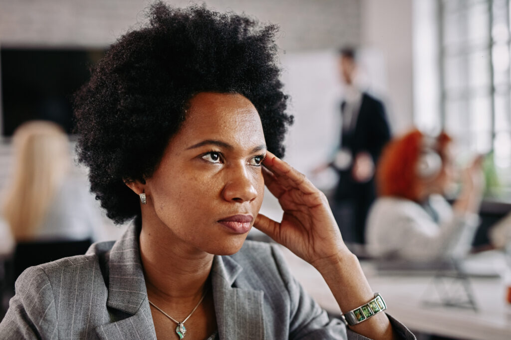 african american businesswoman looking thoughtful while being office there are people background